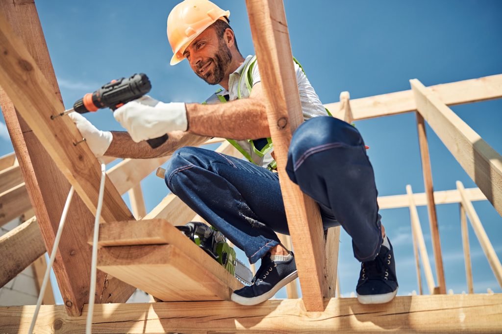 A delighted male worker, clad in a professional uniform, actively engaged in his tasks at a construction site, displaying a positive attitude towards his work
